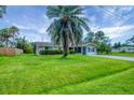 Well-kept single-story home with a large palm tree accenting the front lawn, enhanced by mature landscaping at 386 Nightingale Rd, Venice, FL 34293