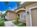 Home exterior showcasing an arched entryway, well-kept lawn, and a lush palm tree at 4150 Otoole St, North Port, FL 34291