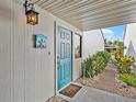 Charming home entrance with a teal door, welcome sign, and lush tropical plants at 500 Park S Blvd # 33, Venice, FL 34285