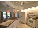 Functional kitchen with white appliances, ample cabinet space, and a breakfast bar overlooking the outdoor living area at 505 Duke Rd, Venice, FL 34293