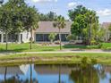 Water view single Gathering home featuring a screened lanai bordered by mature trees and well kept lawn at 511 Wexford Dr, Venice, FL 34293