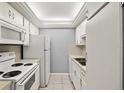 Galley kitchen featuring white appliances, cabinets, and tile flooring at 614 Guild Dr # 10, Venice, FL 34285