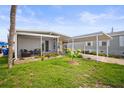 Well-manicured lawn showcasing a home's quaint, covered porch with outdoor seating and colorful flower beds at 614 N Waterway, Venice, FL 34285