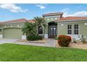Charming exterior of a green home featuring a well-manicured lawn, desert landscaping, and a red tile roof at 6619 Pinefeather Ct, Bradenton, FL 34203