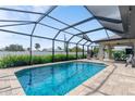 Sparkling blue swimming pool enclosed by a screened lanai with brick pavers and privacy hedges at 7257 Maguire Ln, Englewood, FL 34224