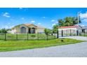 Charming yellow house with a gated entrance, lush lawn, and a clear blue sky at 102 Bayamo Dr, North Port, FL 34287