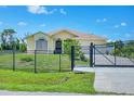 Charming yellow house with a gated entrance, lush lawn, and a clear blue sky at 102 Bayamo Dr, North Port, FL 34287