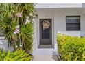 Close-up of the condo entrance with a wreath-adorned door and blossoming plants, creating a warm and inviting ambiance at 1100 Capri Isles Blvd # 215, Venice, FL 34292