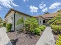 This single-story home features a tile roof, a well-kept lawn, and lovely landscaping at 11192 Campazzo Dr, Venice, FL 34292