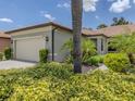 Single-story home with a tile roof, two-car garage, and attractive landscaping at 11192 Campazzo Dr, Venice, FL 34292