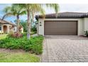 Garage with meticulously maintained landscaping and beautiful pavers at 12187 Amica Loop, Venice, FL 34293