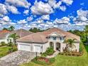 Beautiful home with a tile roof, three-car garage, and a lush lawn with manicured landscaping and brick paver driveway at 12404 Destin Loop, Venice, FL 34293