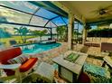 Relaxing screened-in lanai with a pool, spa, fire pit, and plenty of seating overlooking the water at 13092 Rinella St, Venice, FL 34293