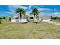 Charming single-story home featuring two palm trees, a green lawn, and a bright white exterior at 20430 Edgewater Dr, Port Charlotte, FL 33952