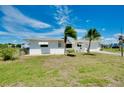 Charming single-story home featuring two palm trees, a green lawn, and a bright white exterior at 20430 Edgewater Dr, Port Charlotte, FL 33952