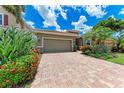 Home featuring a paver driveway leading to a two-car garage, complemented by vibrant landscaping at 2944 Oriole Dr, Sarasota, FL 34243