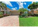Charming home featuring a brick driveway, lush landscaping, palm trees, and green grass at 2944 Oriole Dr, Sarasota, FL 34243