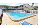 Bright community pool area with lounge chairs surrounded by a white picket fence at 320 Base E Ave # 215, Venice, FL 34285