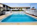 Sparkling community pool area with lounge chairs surrounded by a white picket fence at 320 Base E Ave # 215, Venice, FL 34285