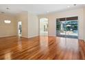Open living room with hardwood floors, neutral walls, arched doorways and a view of the screened-in pool area at 355 Swallow Cir, Venice, FL 34285