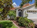 Inviting home exterior with a tile roof, a two-car garage, and lush, verdant landscaping at 4176 Summertree Rd, Venice, FL 34293