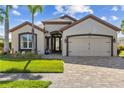 Charming home exterior featuring a brick driveway, manicured lawn, and a well-maintained two-car garage at 4260 Wordsworth Way, Venice, FL 34293