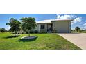 Exterior view of a one story home with a well manicured green lawn and tidy landscaping at 48 Lark Dr, Placida, FL 33946