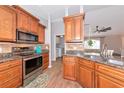 Well-equipped kitchen featuring stainless steel appliances, granite countertops, and wood cabinetry with a tile backsplash at 6964 Glacier Ave, North Port, FL 34291