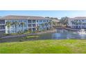 Three-story condo building surrounded by lush green lawns and a serene pond at 700 Gardens Edge Dr # 722, Venice, FL 34285