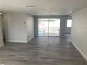 Bright living room with updated gray floors, neutral walls, and sliding glass doors to the pool at 9110 Lunar Ln, Port Richey, FL 34668