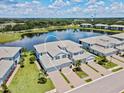 Aerial view of the townhome showcasing the community, lake, landscaping, and paver driveway at 935 Tidewater Shores # 721, Bradenton, FL 34208