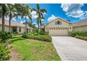 Charming home featuring a well-manicured lawn, lush landscaping, and a two-car garage at 9361 Carnaby Dr, Venice, FL 34293