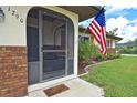 Welcoming front porch with a screen door, American flag, and beautifully landscaped yard, offering great curb appeal at 1290 Leeward Rd, Venice, FL 34293