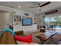Cozy living room features a large built-in shelving unit, wood ceiling fan, and access to the pool at 13862 Miranese St, Venice, FL 34293