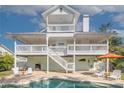 Expansive backyard with a sparkling pool, outdoor seating, and multiple stories of balconies at 334 7Th N Ave, Tierra Verde, FL 33715