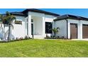 Modern home with a two car garage and a manicured lawn at 24194 Peppercorn Rd, Punta Gorda, FL 33955