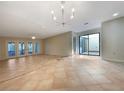 Spacious living room with tile flooring, modern light fixture, neutral color palette, and sliding glass doors at 7483 Carnoustie Dr # 5B, Sarasota, FL 34238