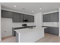 Modern kitchen featuring gray cabinets, stainless steel appliances, and a large white island at 9593 Vibrant Lane, Venice, FL 34292