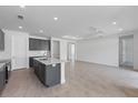 Open-concept kitchen with gray cabinets, a white island, and seamless flow to the living area at 9593 Vibrant Lane, Venice, FL 34292