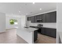 Well-lit kitchen with gray cabinets, a white island, and stainless steel appliances at 9593 Vibrant Lane, Venice, FL 34292