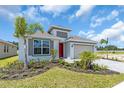 Single-Gathering home featuring a red front door, gray trimmed windows, and low maintenance landscaping at 9577 Vibrant Lane, Venice, FL 34292