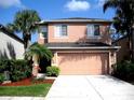Two-story home with a two-car garage, front yard with palm trees, and a well-maintained lawn at 11774 Tempest Harbor Loop, Venice, FL 34292