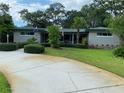 Well-maintained front yard featuring mature trees, manicured hedges, and a spacious driveway leading to the home at 3240 San Mateo St, Clearwater, FL 33759
