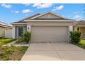 Tan one-story house with a two-car garage and grey front door at 12120 Barnsley Reserve Pl, Gibsonton, FL 33534