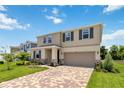 Two-story house with a neutral color scheme, landscaping, and a brick paver driveway at 9034 Sandy Bluffs Cir, Parrish, FL 34219