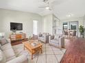 Bright living room featuring modern furniture, a ceiling fan, and hardwood floors leading to an eat-in dining area at 7087 Spinnaker Blvd, Englewood, FL 34224