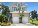 Tan three-story house, two car garage, and tropical landscaping at 1340 Apollo Beach S Blvd, Apollo Beach, FL 33572