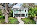 Two-story light teal home with a wrap around porch at 210 15Th E St, Bradenton, FL 34208