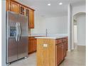 Modern kitchen featuring an island, tile floors, stainless steel refrigerator and custom wood cabinetry at 2302 123Rd E Pl, Parrish, FL 34219