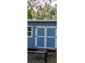 Blue storage shed with double doors and a single window at 7804 Chasco St, Port Richey, FL 34668
